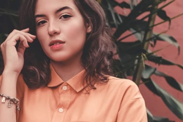 A stylish young woman with an apricot shirt poses for the camera.